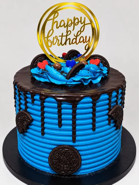 Blue birthday cake with chocolate drip and biscuit decorations