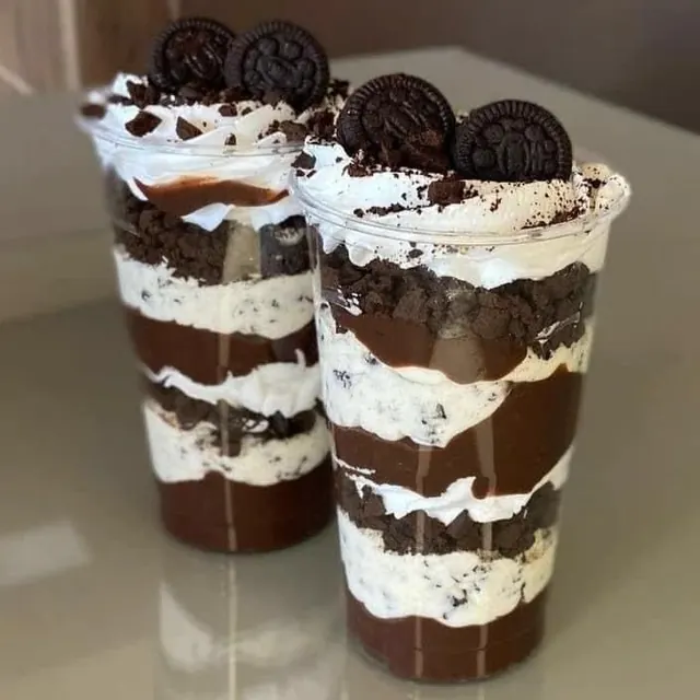 Layered chocolate and cream cake parfaits topped with biscuits