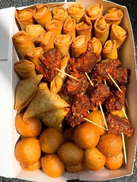 Box of assorted small chops with samosas, puff puff and skewers